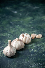 front view fresh garlics lined on the gray background greens plant vegetable sour seasoning food pepper