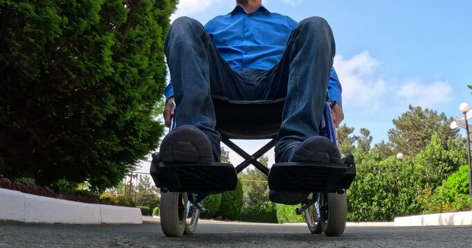 Disabled person in a wheelchair moves along the road not for a walk in the summer.