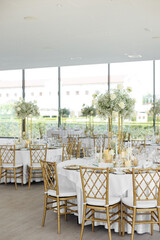 Served wedding tables with golden plates, decorative fresh  white roses and gypsophila flowers and different candles. Celebration details. Wedding decoration and decor, floristic concept	
