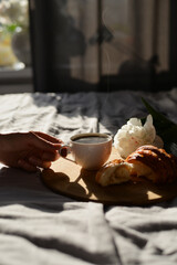 women hand taking cup of coffee in the morning in bed