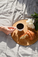 women hand taking cup of coffee in the morning in bed
