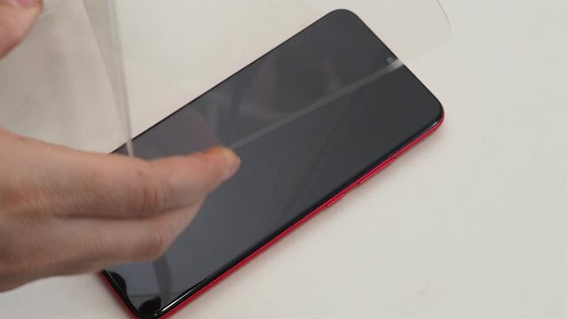 The woman replacing the broken tempered glass screen protector for smartphone. wears a screen protector. Cleans the phone screen with a tissue.