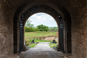 Archway in the fortress wall. Bridge and a landscape behind the wall.