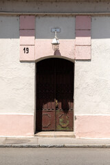 Old door in the white wall with the pink details around it.