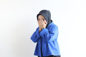 Beautiful young Asian Muslim woman, wearing glasses and blue blazer with hand gesturing to cover face