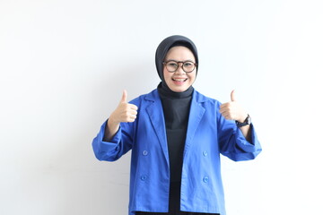 beautiful young Asian Muslim woman, wearing glasses and blue blazer with hand gesture of approval or OK