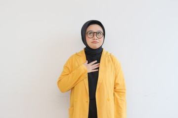 Beautiful young Asian Muslim woman in glasses and smiling putting both hands on chest and showing affection gesture isolated over white background