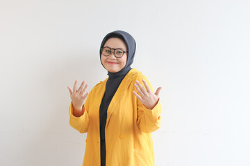 Young beautiful Asian Muslim woman, wearing glasses and yellow blazer with happy smiling face expression