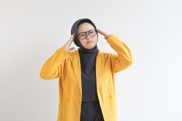 Beautiful young Asian Muslim woman, wearing glasses and yellow blazer is scratching head with confused expression