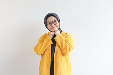 Young beautiful Asian Muslim woman, wearing glasses and yellow blazer with happy smiling face expression