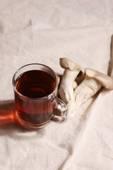 Natural medicine, reduce stress and improve immunity concept. Mushroom hot drink. Tea in glass mug with mushrooms on textile background. Copy space. 