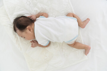 Obraz na płótnie Canvas Top view of newborn baby sleeping on blanket on white bed. Infant lying on white bed. Asian newborn baby sleeping in prone position. Asian infant