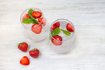 Water with strawberry and mint. Ice cold summer cocktail or lemonade in glass. Detox and diet. 