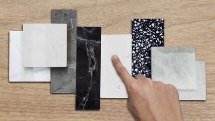 interior designer's hand selects premium stone samples including black marble, grey artificial...