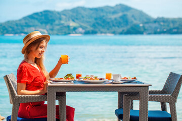 Young woman on holiday vacation enjoys a morning meal with healthy food in a luxury resort restaurant. Thailand vacation.