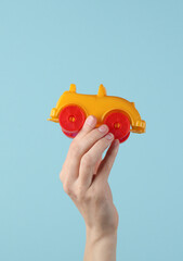 Hand holding a toy car on a blue background