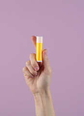 Woman's hand holds tube of lip balm on pastel background