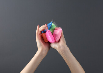 Female hands holding package of molecular colored plasticine on a dark background