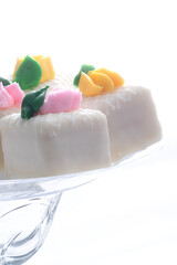 White petit fours on a white background with pink and yellow flowers