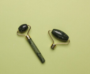 Jade rollers for anti-aging face lifting massage on a green background. Minimalism beauty still life