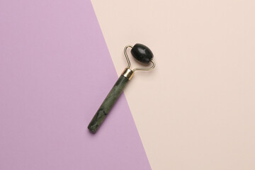 Jade massage roller for anti-aging face lifting on a pastel background. Minimalism beauty still life