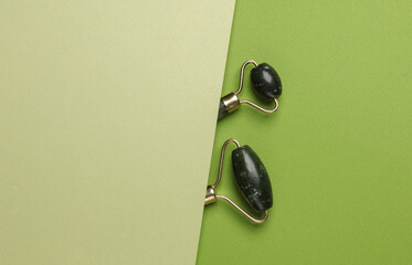 Jade rollers for anti-aging face lifting massage on a green background. Minimalism beauty still life