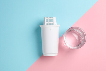Cartridge filter for filtering water and a glass of clean water on pink blue background. Health...