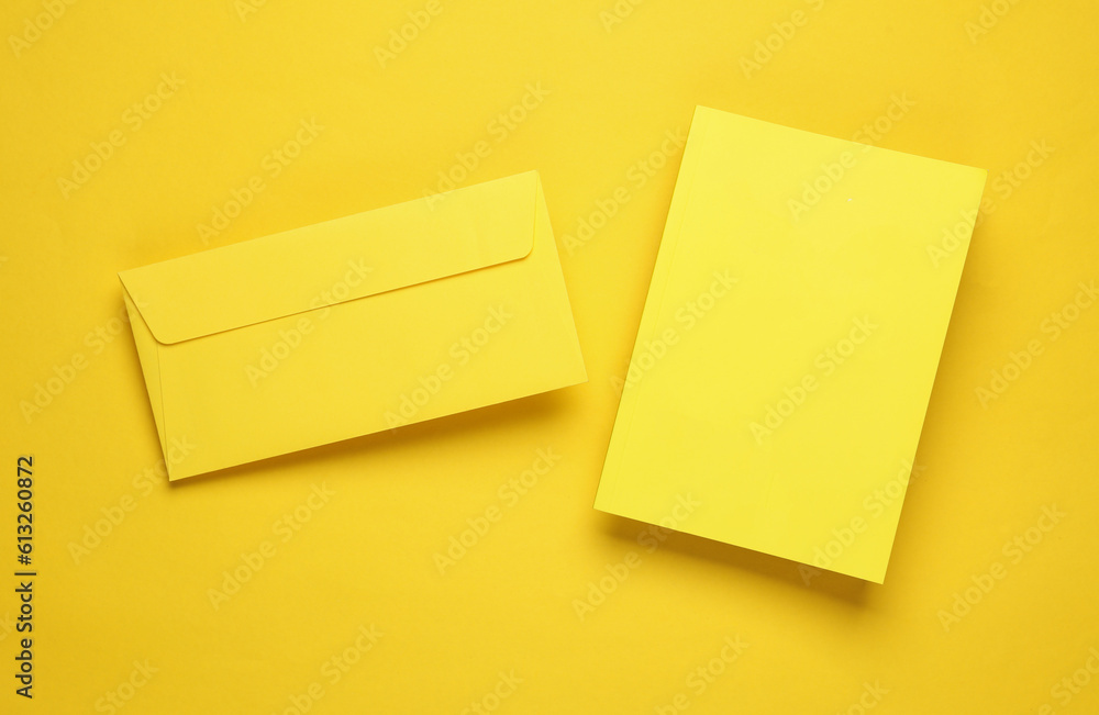 Poster notepad with a yellow cover and envelope floating on a yellow background