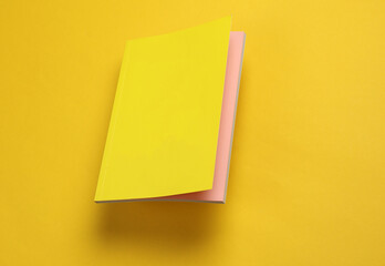 Notepad with a yellow cover floating on a yellow background