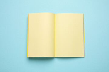 Blank open notepad or notebook with yellow sheets on blue pastel background