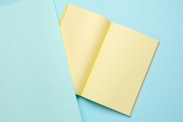 Blank open notepad or notebook with yellow sheets on blue pastel background