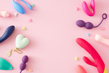 Obraz na płótnie Canvas Concept of adult toys for sexual satisfaction. Top view of vibrator, vaginal balls, dildo, clitoral stimulators and hearts on pastel pink background with an empty space for text or promotional