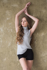 Young fashion woman posing near grey wall
