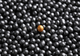 Bronze ball among dark powder balls close-up. Beauty concept