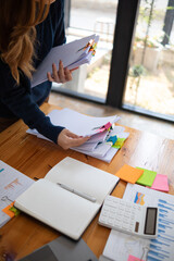 secretary searches through stacked documents on desk in office to find lease within stacked...