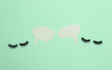 False eyelashes with dialog clouds on blue background. Minimal still life