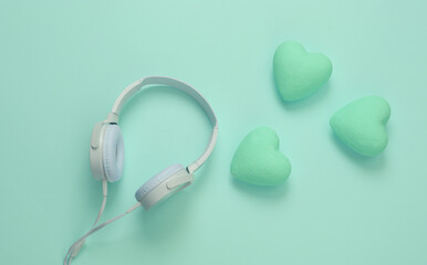 Headphones with hearts on blue background. Romantic melody. Top view