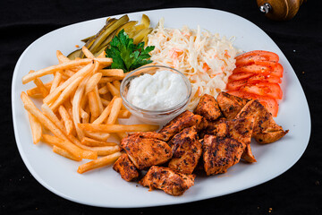 Dinner fried chicken fillet with coleslaw, French fries, tomatoes, pickled cucumbers and sauce.