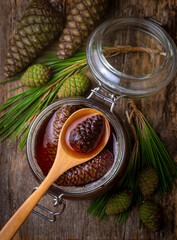 Young pine cones jam in glass bowl on wooden board. Delicious jam with the little pine cones.