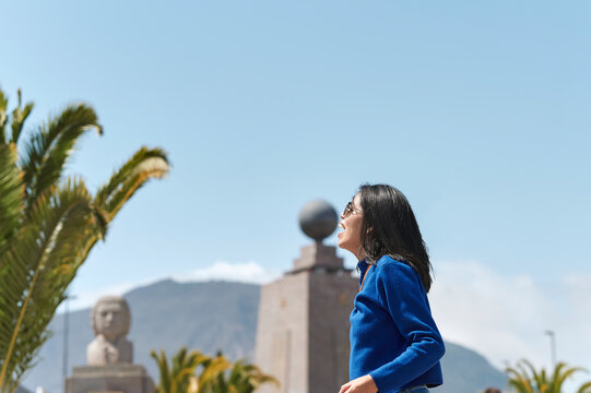 Woman biting the Mitad del Mundo monument in Ecuador