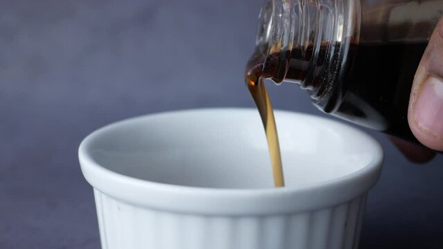 Bottle of maple syrup pouring close up 