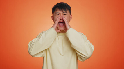 Asian handsome man scream yell with hand near mouth greeting with hand as notices someone. Adult...