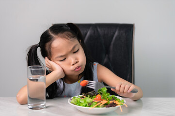 Little asian cute girl refuses to eat healthy vegetables.Nutrition & healthy eating habits for kids concept.Children do not like to eat vegetables.
