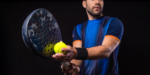 Padel tennis player with racket. Man athlete with paddle racket on black background. Sport concept. Download a high quality photo for sports website. © Mike Orlov