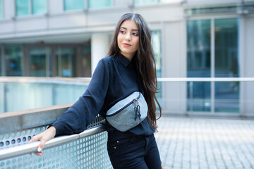 trend fashion teenage girl look to side and pose with her grey noname fanny pack at shoulder while...