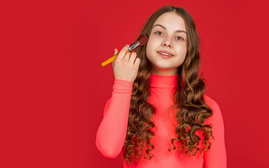 positive child with curly hair apply powder on face with makeup brush