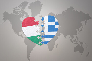 puzzle heart with the national flag of greece and hungary on a world map background.Concept.