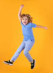 Full length of excited kid jumping. Kid boy 8-9 years old in t-shirt jump isolated on yellow background. Childhood lifestyle concept. Mock up copy space. Kid having fun, jumping.