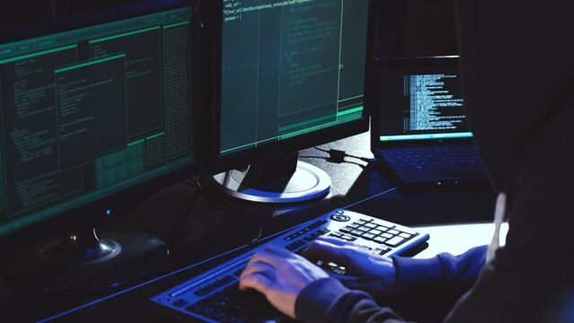 Back hooded hacker using malicious software hack corporate data center. malefactor hidden underground in dark place, multiple displays with phishing code and global map attack.
