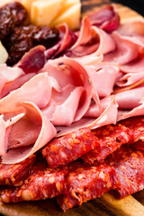 Various types of meat slices of sausage, ham, cheese, sun-dried tomatoes and bread.